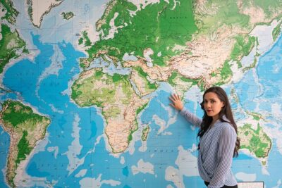 Educator in Front of the World Map of Destinations